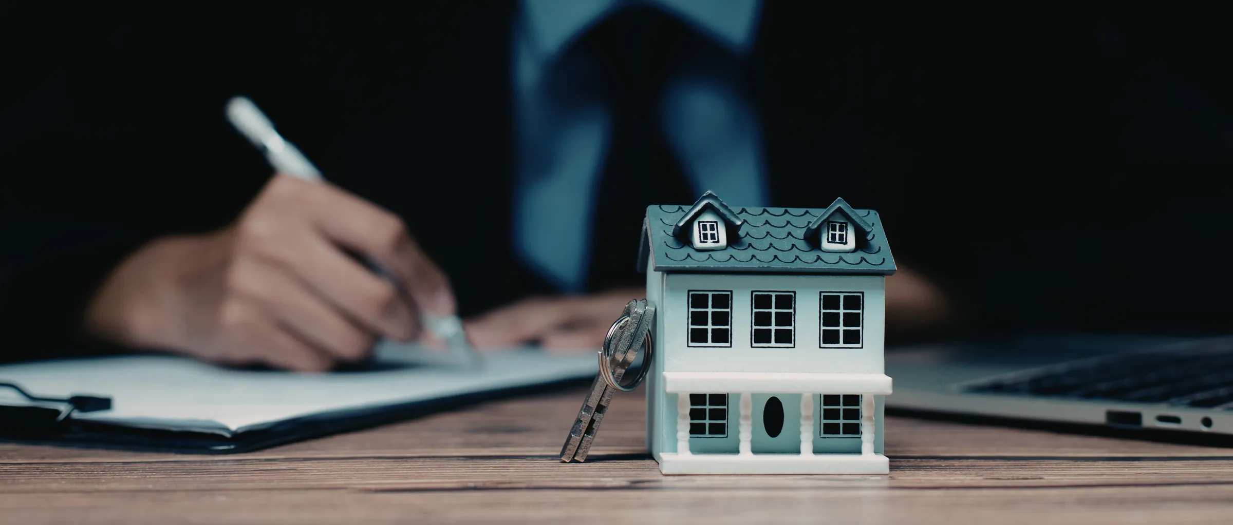 Immobilienbewertung – Modellhaus und Schlüssel auf Schreibtisch